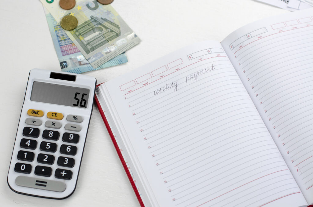 Blank notepad with the inscription Pay utility bills, calculator and money on the table